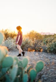 a woman in a hat walking through the desert