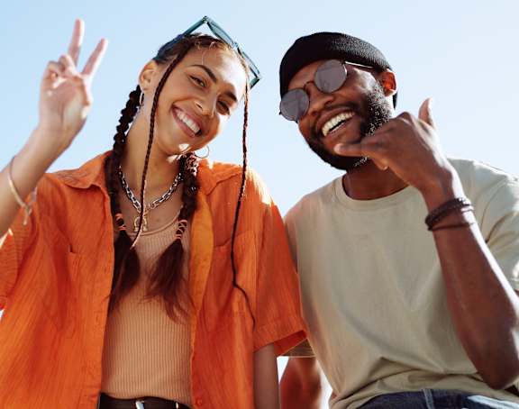 Two people are standing together with peace signs.