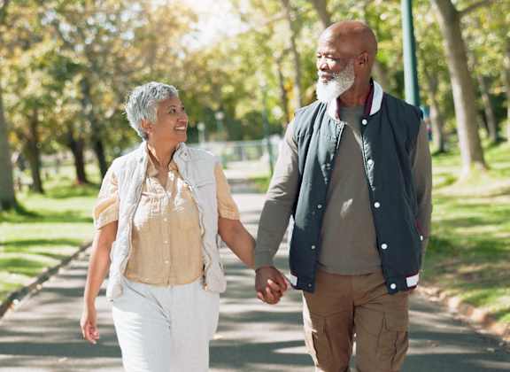 a man and a woman walking down a path in a park