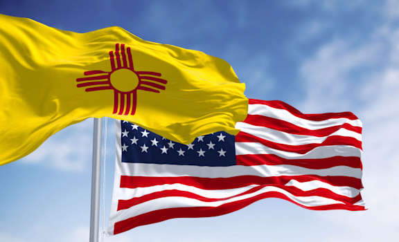 flags flying in the wind against a blue sky
