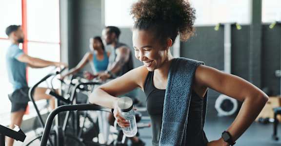 A woman is standing in front of a stationary bike in a gym.