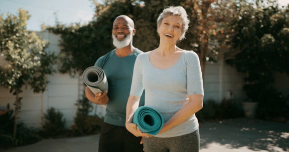 a man and a woman holding yoga mats at Heritage at Church Ranch 55+ Apartments, Westminster , 80021