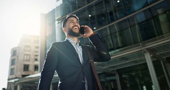 A man in a suit is talking on a phone in front of a building.