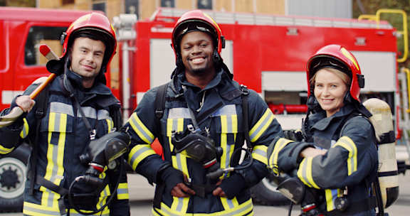 Three firefighters in front of a fire truck.