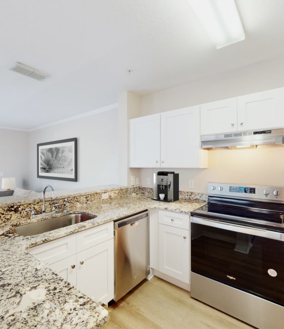 a kitchen with white cabinets and granite countertops at Audubon Oaks, Lakeland