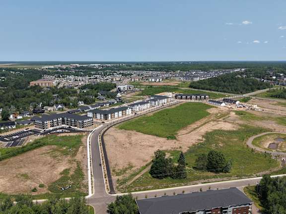 A row of apartment buildings with cars parked in front.