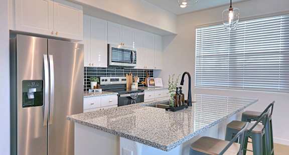 A modern kitchen with a stainless steel refrigerator and granite countertops.