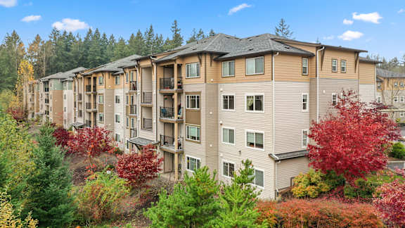 A row of apartment buildings with trees in the foreground. at Meadows at Heron Creek, Oregon