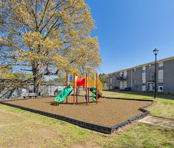 A playground with a slide and swings in a grassy area.
