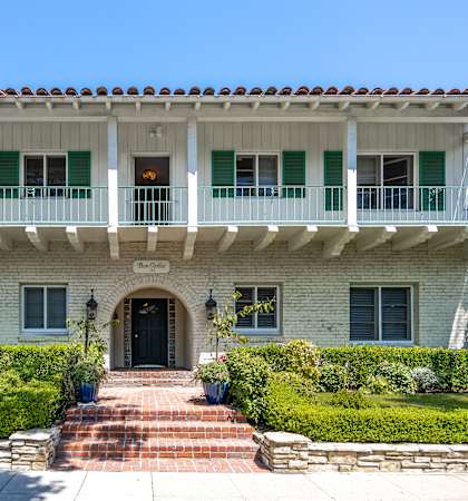a mansion with a white brick facade and green shutters