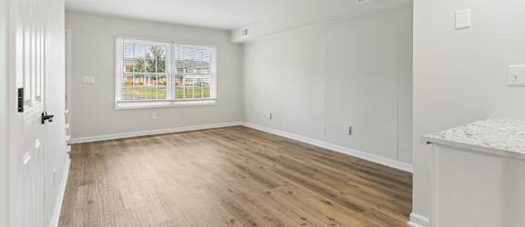 A room with wooden flooring and white walls.