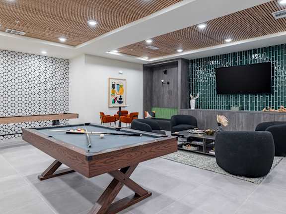 A billiard table is in the middle of a room with a television and a pool table at The Collective Upper Westside Apartments, Atlanta, GA, 30318