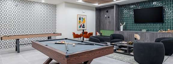 A billiard table is in the middle of a room with a television and a pool table at The Collective Upper Westside Apartments, Atlanta, GA, 30318