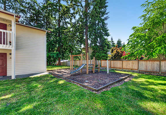 A backyard with a playground and a fence.