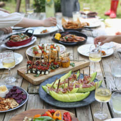 a group of people sitting around a picnic table eating food