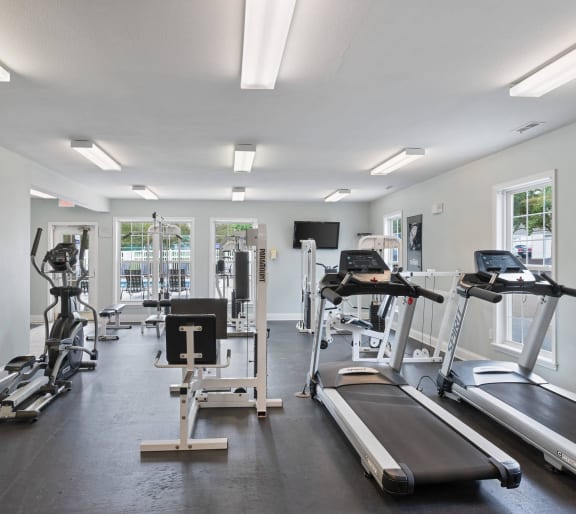 a gym with cardio equipment and a flat screen tv