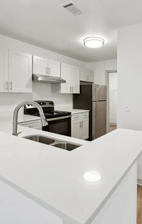 A white kitchen with a sink and a refrigerator.