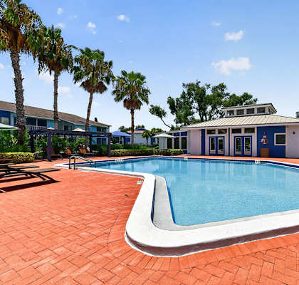 A swimming pool surrounded by palm trees and a building.