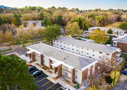 an aerial view of a building with a parking lot and trees
