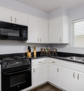 a kitchen with white cabinets and black countertops
