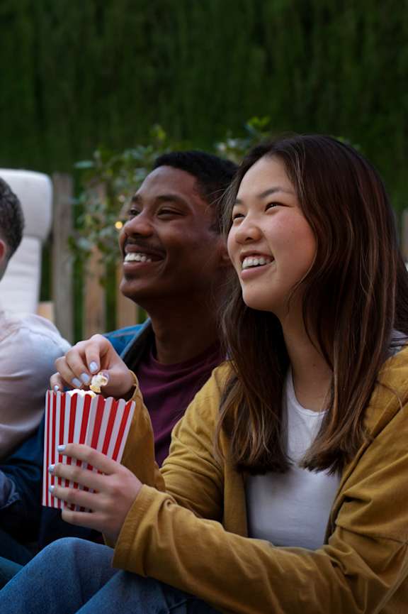 Four people are sitting outside and watching a movie at Alameda Apartments, Wembley, HA9 0HS