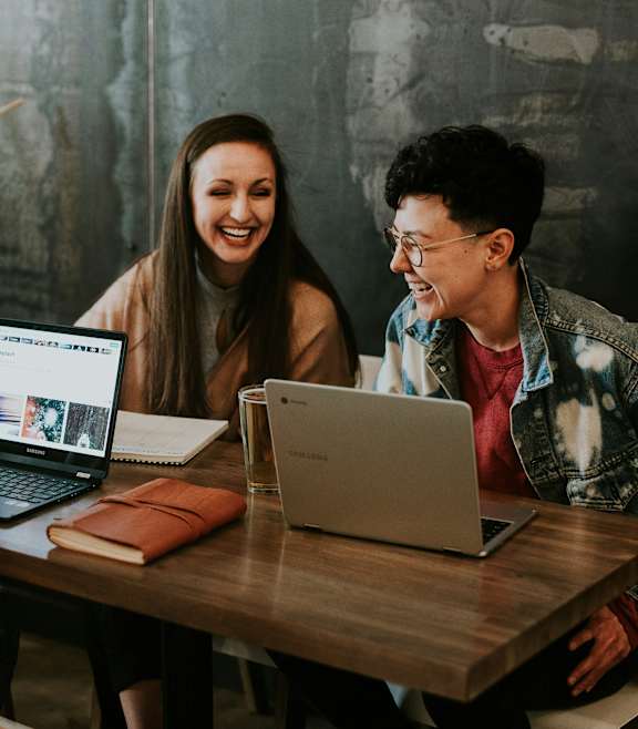 Three people are sitting at a table with laptops open in front of them.