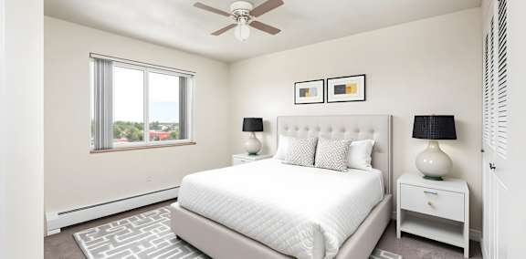 A bedroom with a large bed, a ceiling fan, and two lamps.