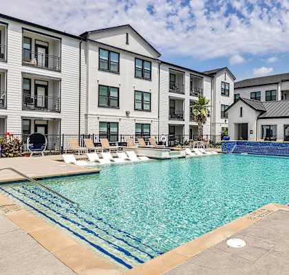 A large swimming pool in front of apartment buildings.