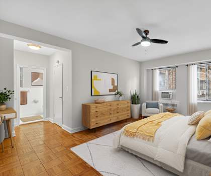 A bedroom with a bed, a couch, a ceiling fan, and a wooden dresser.