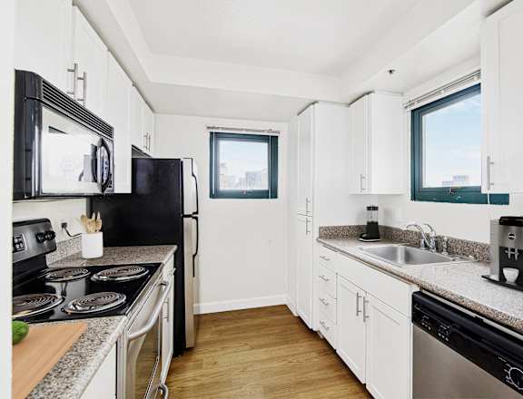 a kitchen with granite counter tops and black appliances and white cabinets