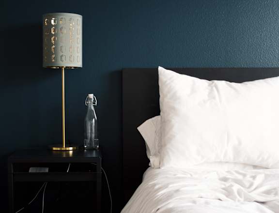 a bedroom with blue walls and a bed with a white pillow and a nightstand