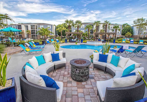 A poolside area with wicker chairs and a fire pit.