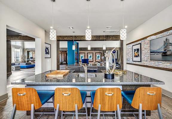 A kitchen with a large island and blue chairs.