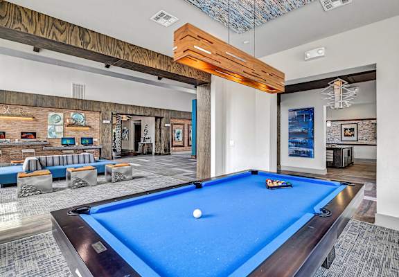 A pool table is in the middle of a room with a blue carpet.