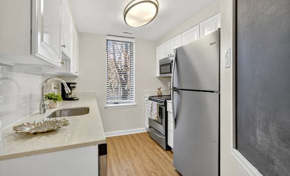 A kitchen with a refrigerator, sink, and window.