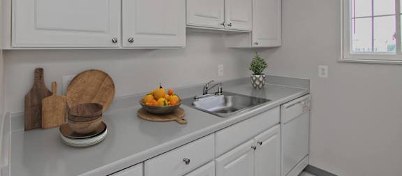 A kitchen with white cabinets and a countertop with a bowl of fruit on it. at Dulles Glen Apartments, Herndon, VA
