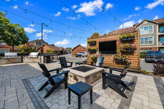 A patio with a hot tub and chairs is surrounded by a black fence.