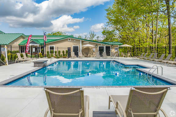 A swimming pool with chairs around it and a building in the background.
