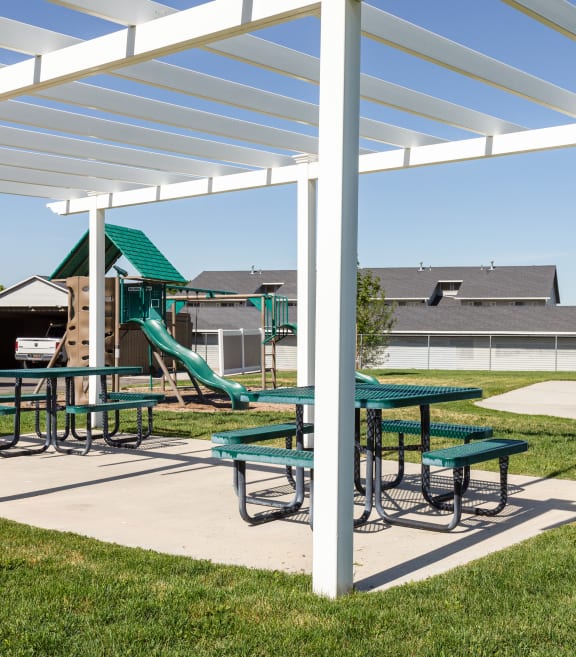 a picnic area with picnic tables and a playground in the background