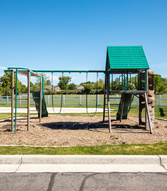 a playground with a monkey bars swing set and basketball hoop