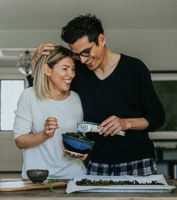 A man and woman are preparing food together in a kitchen.