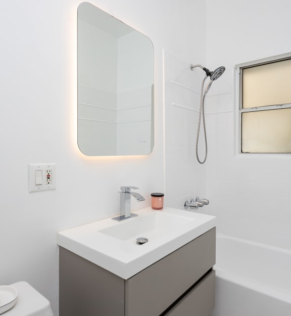 a bathroom with white walls and a white sink with a mirror above it