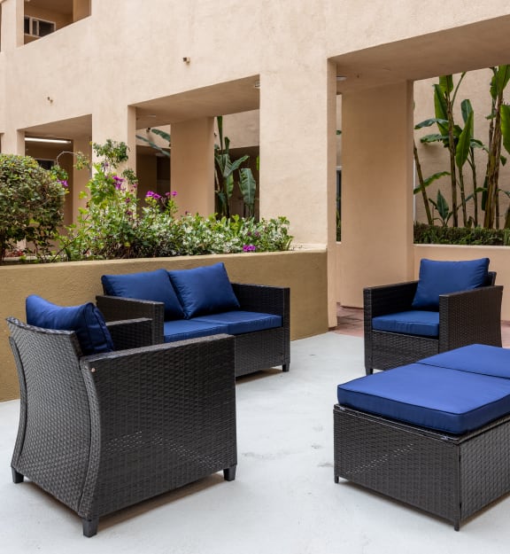 a seating area with two chairs and a coffee table on a concrete patio in front of a