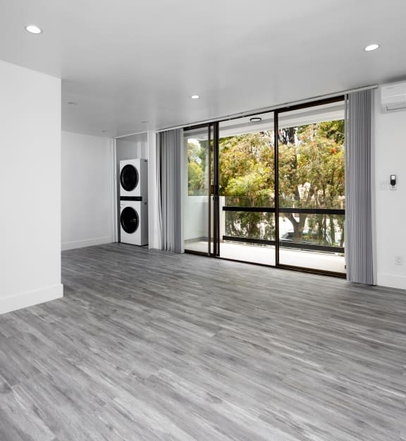 a living room with white walls and grey flooring