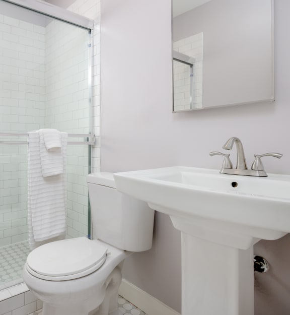 a bathroom with white tiles and a white sink and toilet