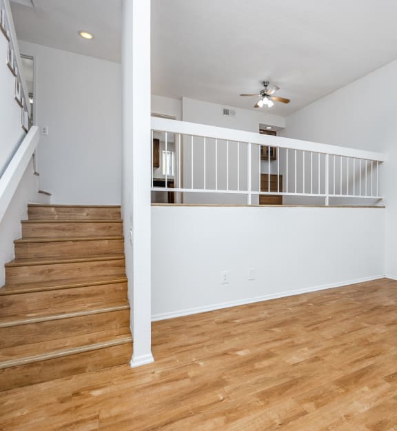 a bedroom with hardwood floors and a staircase