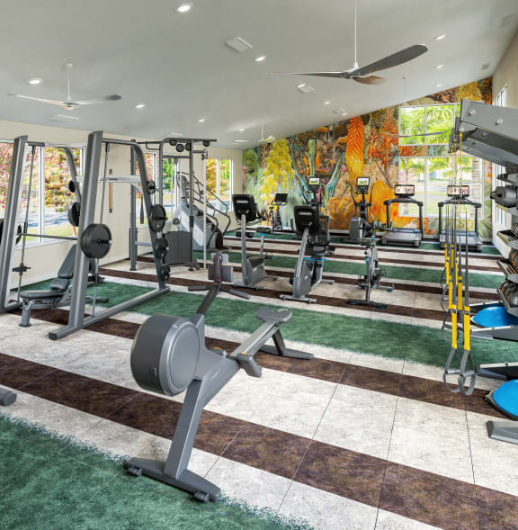 a gym with weights and cardio equipment on the floor and a painting on the wall