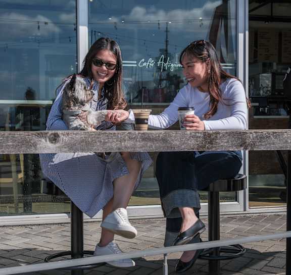 Two women sitting at a table with a dog.