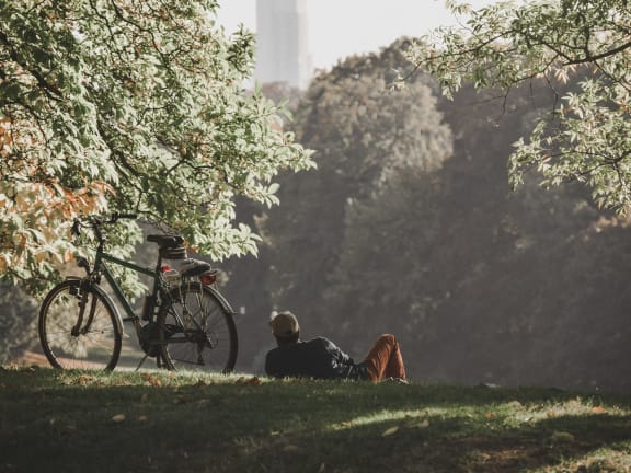 a man laying in a park next to a bike