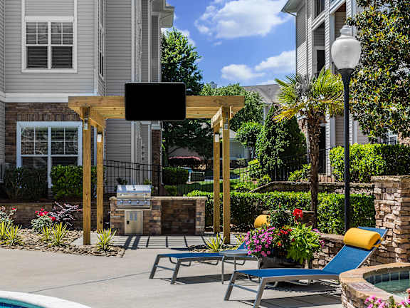 A patio with a table and chairs overlooking a pool.